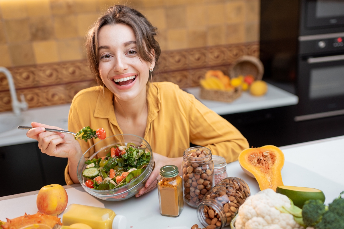 devojka jede salatu iz činije oko nje dektoks sokovi badem i lešnik